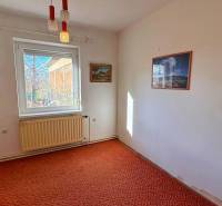 Ein Zimmer in einem Einfamilienhaus, mit Teppichboden, weißem Heizkörper, Bilder an den Wänden.