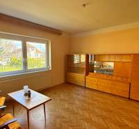 Wohnzimmer in einem Einfamilienhaus mit Möbeln und Boden in Holzoptik.