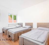 Drei Betten in einem Zimmer mit Holzboden und einem Bild an der Wand.