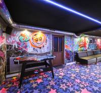 Innenraum eines Gebäudes mit Graffiti an den Wänden, bunten Teppichen und einem Tischhockey.