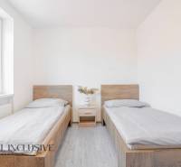 Ein Zimmer mit zwei Betten, einem Nachttisch und einem Boden in Holzoptik.