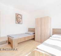 Schlafzimmer mit zwei Betten und Möbeln, Holzboden, Bild an der Wand.