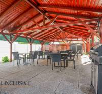 Außenterrasse eines Gebäudes in Dunajská Streda mit einem Holzdach und einem Grill.