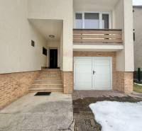Ein Einfamilienhaus in Čadečka in Čadca mit Treppen und einer Garage, Schneereste auf der Zufahrtsstraße.