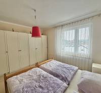 Schlafzimmer in einem Einfamilienhaus mit Bett, großem Schrank und Vorhängen.