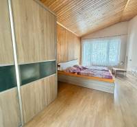 Schlafzimmer in einem Einfamilienhaus mit Holzboden, Bett und großem Fenster.