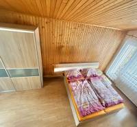 Schlafzimmer im Einfamilienhaus mit Holzverkleidung, Boden mit Holzdekor, großes Fenster.