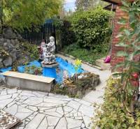 Der Garten des Ferienhauses im Košicer Stadtteil Vyšné Opátske mit einem Ziegelhäuschen und einer Statue.