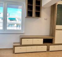 Wohnwand in einer Einzimmerwohnung mit Holzboden und Blick aus dem Fenster.