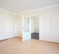 Ein Zimmer in einem Einfamilienhaus mit weißen Wänden und einem Boden in Holzoptik.