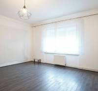 Ein Zimmer in einem Einfamilienhaus mit einem Boden in Holzoptik und einem großen Fenster.