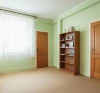 Ein Zimmer in einem Einfamilienhaus mit einer Bibliothek, grünen Wänden und Türen mit Holzdekor.