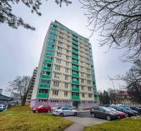 Hochhaus an der Straße SNP in Banská Bystrica mit einem Parkplatz im Vordergrund.