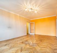 Wohnzimmer mit Holzboden und orangefarbener Wand in einer Zweizimmerwohnung.
