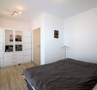 Schlafzimmer in einer 2-Zimmer-Wohnung mit Holzboden, Kleiderschrank und Bett.