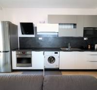 Küche in einer 2-Zimmer-Wohnung mit grauen Schränken, Geräten und einem Boden in Holzoptik.