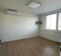 Ein Zimmer mit weißen Wänden und einem Boden in Holzoptik in einer Einzimmerwohnung.