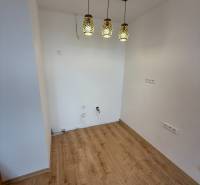 Innenraum einer Einzimmerwohnung mit Holzboden und Hängelampen.