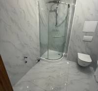 Badezimmer mit Marmorkacheln und Duschkabine in einer Einzimmerwohnung.