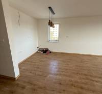 Ein Zimmer einer 2-Zimmer-Wohnung mit einem Boden in Holzoptik und hängenden Leuchten.