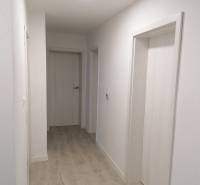 Ein schmaler Flur in einem Einfamilienhaus mit weißen Wänden und einem Boden in Holzoptik.