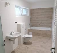 Badezimmer in einem Einfamilienhaus mit Holzboden, Badewanne und Waschbecken.