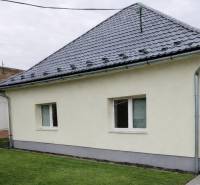 Ein Einfamilienhaus in Bernolákovo mit Rasen, grauem Dach und heller Fassade.