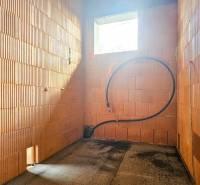 Unvollendeter Innenraum in einem Einfamilienhaus mit Sichtmauerwerk und einer Öffnung für ein Fenster.