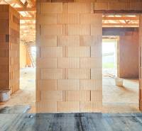 Der Innenraum eines im Bau befindlichen Einfamilienhauses mit unverputzten Ziegelwänden und Blick nach draußen.