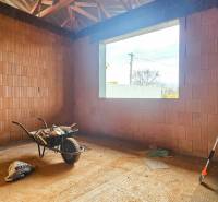 Interieurräume in einem Einfamilienhaus mit Ziegelwänden, einer Schubkarre und Werkzeugen.