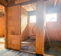 Der Innenraum eines im Bau befindlichen Einfamilienhauses mit Ziegelwänden und Dachträgern.