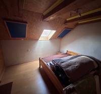 Dachbodenschlafzimmer mit Bett und Dachfenster in einem Einfamilienhaus, Boden mit Holzdekor.