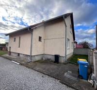Ein Einfamilienhaus in Zbehy mit einer Nebenstraße, einem Rasen und einem blauen Mülleimer.