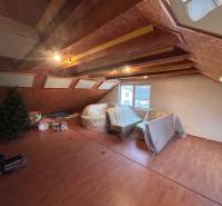 Ein Dachzimmer in einem Einfamilienhaus mit einem Boden in Holzoptik und Dachfenstern.