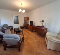 Wohnzimmer einer 3-Zimmer-Wohnung mit Holzboden, Retro-Möbeln und bequemen Sesseln.