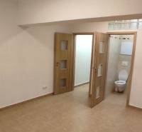 Innenraum einer Einzimmerwohnung mit Keramikfliesen und sichtbarem Badezimmer durch die Tür.