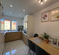 Küche in einer 2-Zimmer-Wohnung, helle Fliesen, Tisch mit Dekorationen, Bilder an der Wand.