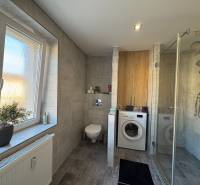 Badezimmer in einer 2-Zimmer-Wohnung mit Waschmaschine, Dusche und Fenster.