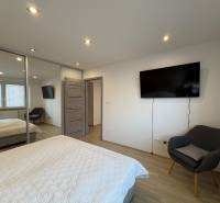 Zweizimmerwohnung mit Fernseher, Kleiderschrank und Holzboden.