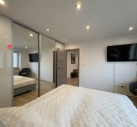 Schlafzimmer in einer 2-Zimmer-Wohnung mit Fernseher, großem Schrank und Holzboden.