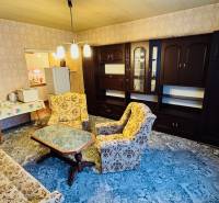 Wohnzimmer in einer Zweizimmerwohnung mit älteren Möbeln und einem Teppich auf dem Boden.