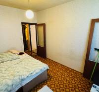 Schlafzimmer mit Teppich, Bett und hellen Wänden in einer 2-Zimmer-Wohnung.