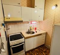 Küche in einer 2-Zimmer-Wohnung, weiße Schränke, Herd, Spüle, Boden mit Holzdekor.