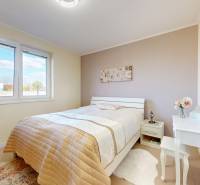 Ein Schlafzimmer in einem Einfamilienhaus mit einem Bett, einem Schminktisch und sanften Farben.