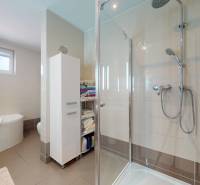 Ein Badezimmer in einem Einfamilienhaus mit Badewanne, Dusche und Lagerregalen.