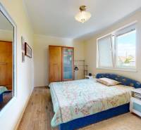 Schlafzimmer in einem Einfamilienhaus mit Holzboden, Spiegel und Bett.