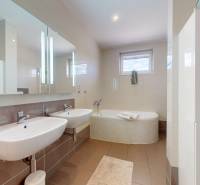 Badezimmer in einem Einfamilienhaus mit Doppelwaschbecken, Badewanne und Keramikfliesen.