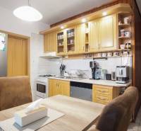 Küche in einer 3-Zimmer-Wohnung mit heller Küchenzeile, Elektrogeräten und einem Tisch mit Stühlen.