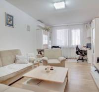 Wohnzimmer mit Sofa und Fernseher in einer 3-Zimmer-Wohnung, Boden mit Holzdekor.