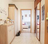 Flur in einer 3-Zimmer-Wohnung mit Fliesenboden und gemütlichen Möbeln in Holzdekor.